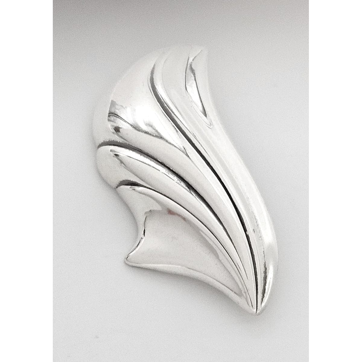 Silver brooch with a leaf-like design on a light gray background
