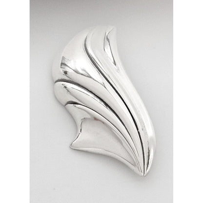 Silver brooch with a leaf-like design on a light gray background