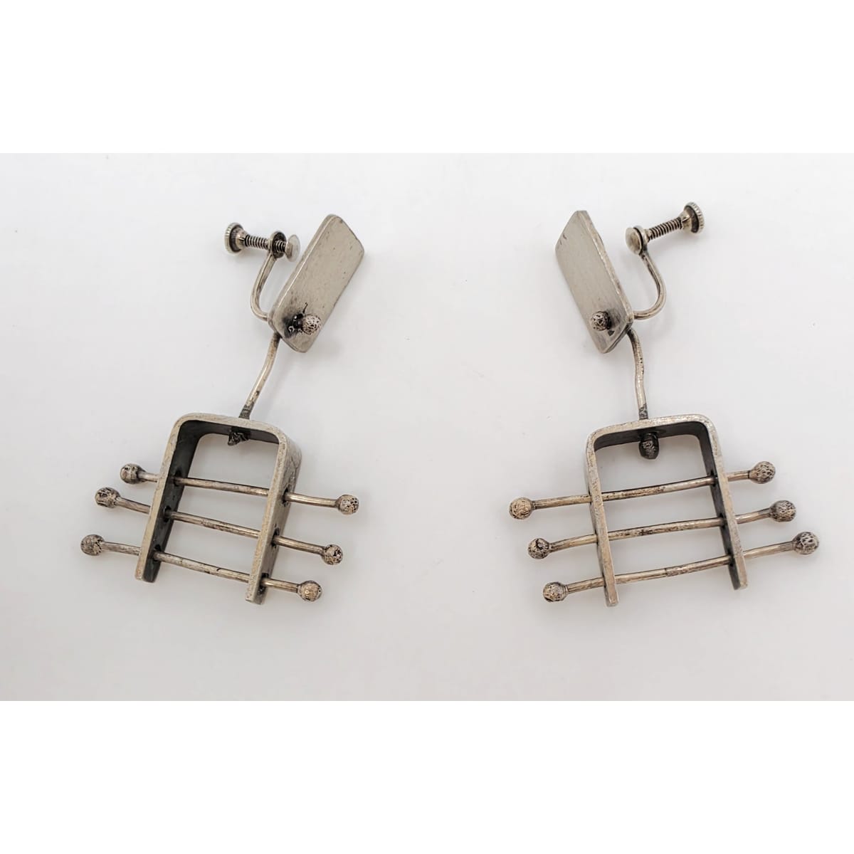 A pair of vintage silver-toned drop earrings with a geometric, guitar-fret-like design featuring horizontal bars and small round tips, photographed on a plain white background.