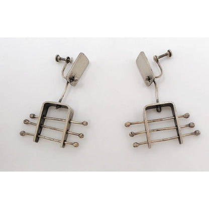 A pair of vintage silver-toned drop earrings with a geometric, guitar-fret-like design featuring horizontal bars and small round tips, photographed on a plain white background.